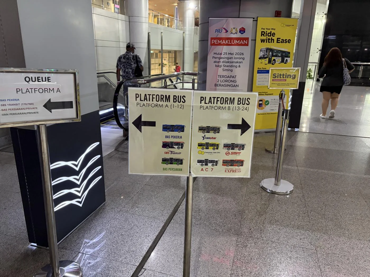 0:43に撮ったJB側のバス乗り場案内。Platform A・Bと会社別の矢印、Standing・Sittingの表示が並んでいた